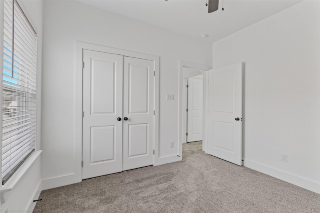 unfurnished bedroom with a ceiling fan, a closet, baseboards, and carpet flooring