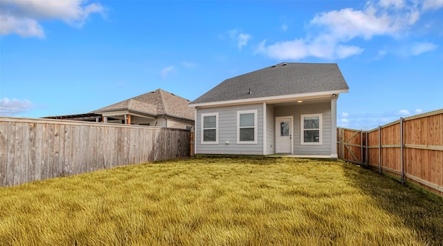 rear view of property featuring a fenced backyard, a shingled roof, and a lawn