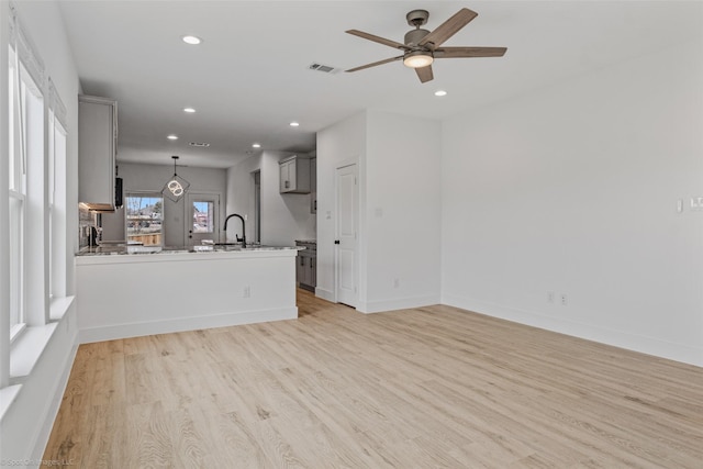 unfurnished living room with recessed lighting, visible vents, a sink, light wood-type flooring, and baseboards