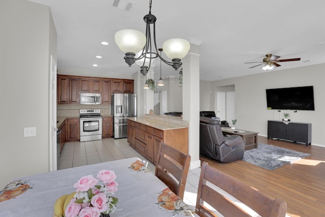 kitchen featuring brown cabinetry, visible vents, stainless steel appliances, and open floor plan