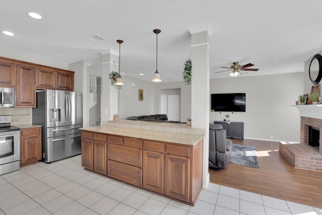 kitchen featuring light tile patterned floors, stainless steel appliances, visible vents, a brick fireplace, and open floor plan