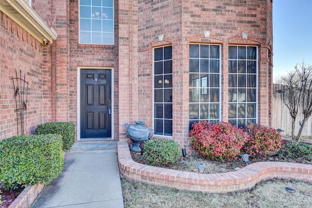 doorway to property with brick siding and fence