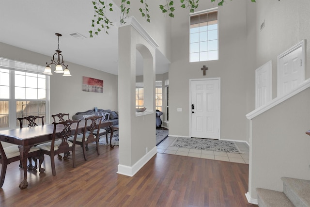 foyer entrance with baseboards, visible vents, arched walkways, and wood finished floors