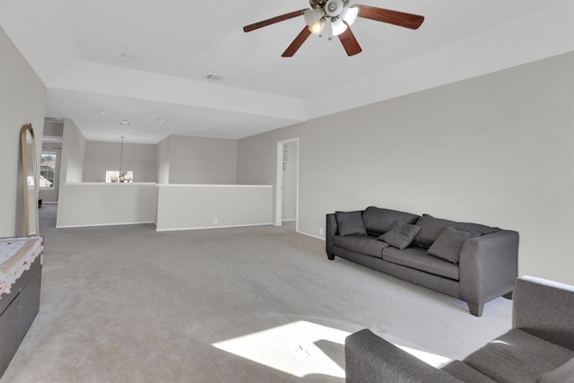 living area with baseboards, ceiling fan with notable chandelier, visible vents, and light colored carpet