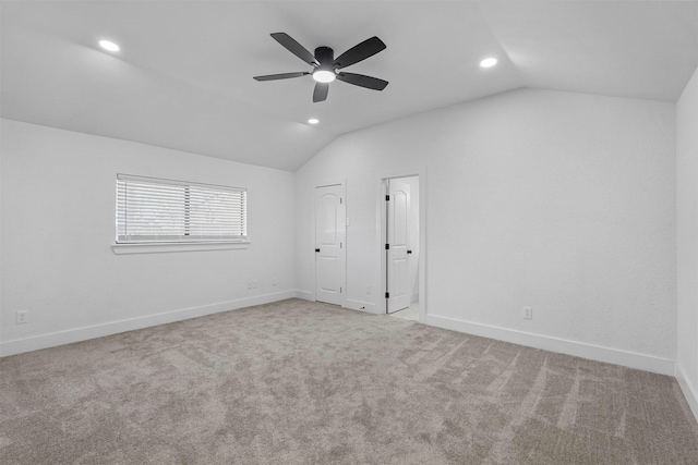 carpeted spare room with lofted ceiling, a ceiling fan, and baseboards