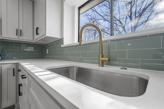 details with light countertops, a sink, white cabinetry, and decorative backsplash