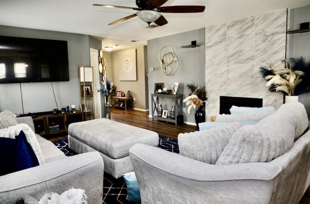 living area with a premium fireplace, wood finished floors, a ceiling fan, and baseboards