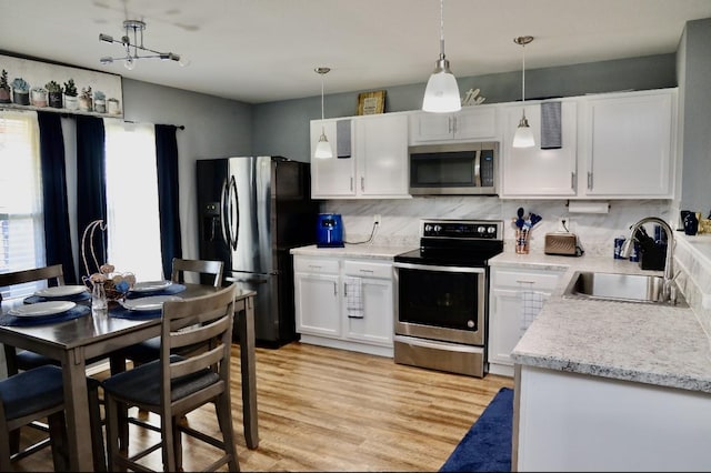 kitchen with stainless steel appliances, light wood-type flooring, a sink, and white cabinets