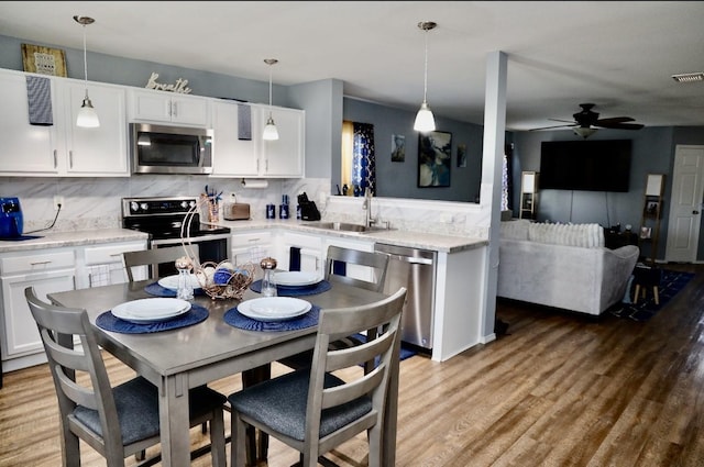 kitchen featuring light wood-style floors, backsplash, stainless steel appliances, and a sink