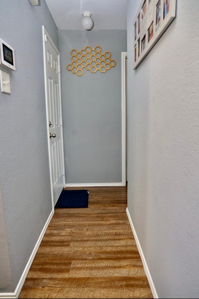 hall with baseboards and wood finished floors