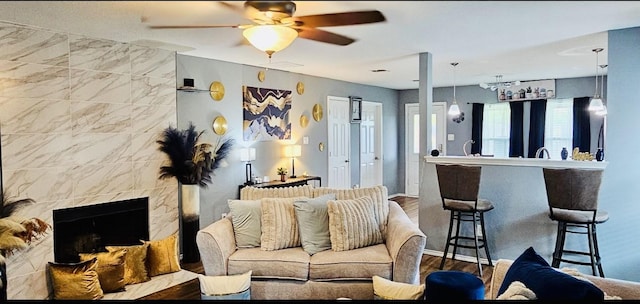 living room with a fireplace, wood finished floors, a ceiling fan, and baseboards
