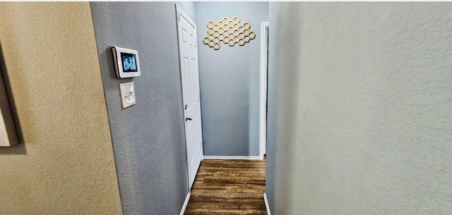 corridor with a textured wall and wood finished floors