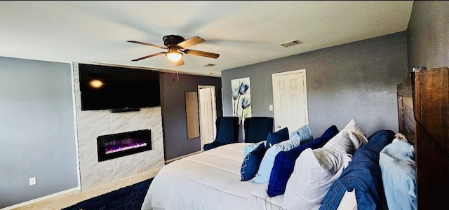 bedroom with baseboards, a tile fireplace, visible vents, and a ceiling fan