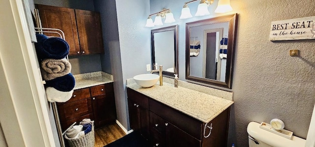 bathroom with a textured wall, wood finished floors, vanity, and toilet