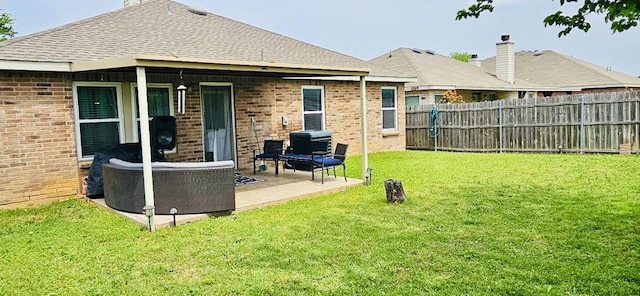 back of house with fence, roof with shingles, a patio area, a lawn, and brick siding
