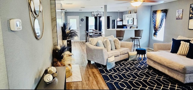 living room with ceiling fan, baseboards, and wood finished floors