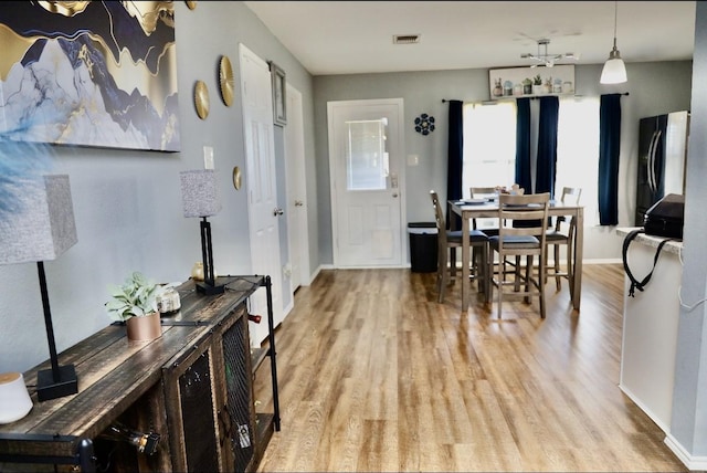 dining area featuring light wood-style floors, baseboards, and visible vents