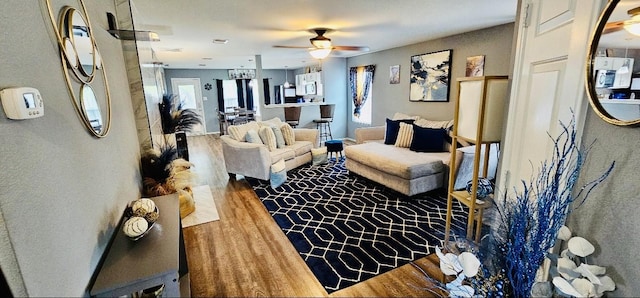 living area featuring wood finished floors, a healthy amount of sunlight, and a ceiling fan