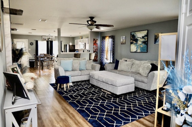 living room with a ceiling fan, visible vents, and wood finished floors