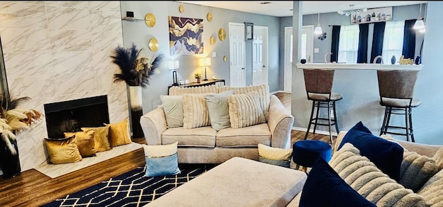 living area featuring a high end fireplace, baseboards, and wood finished floors
