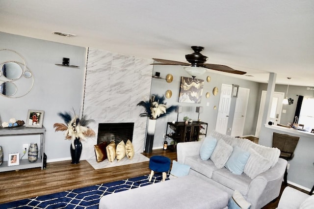 living room with baseboards, a premium fireplace, visible vents, and wood finished floors