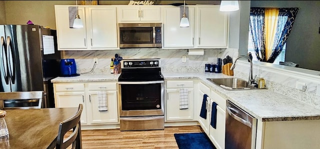 kitchen with light wood-type flooring, stainless steel appliances, white cabinets, and a sink