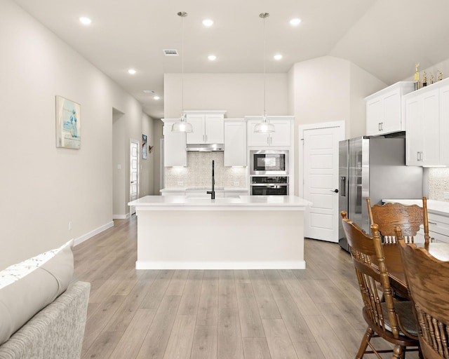 kitchen with light wood finished floors, visible vents, decorative backsplash, appliances with stainless steel finishes, and under cabinet range hood