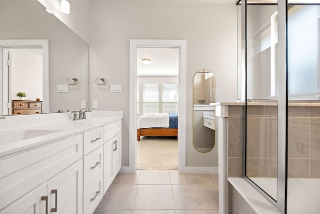 bathroom featuring tile patterned flooring, tiled shower, a sink, and double vanity