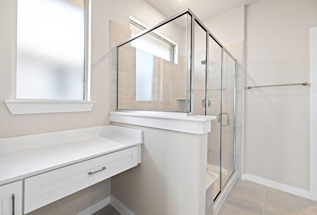 full bath with a shower stall, baseboards, and tile patterned flooring