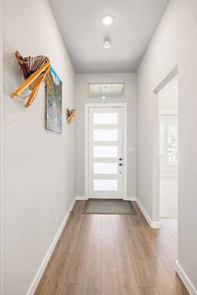 doorway with baseboards and wood finished floors