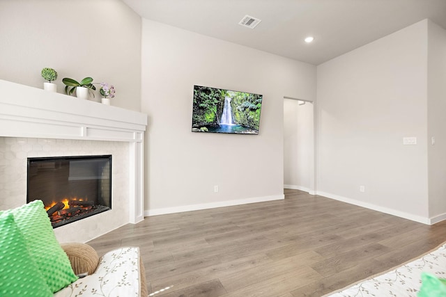 living area featuring recessed lighting, visible vents, baseboards, light wood-type flooring, and a glass covered fireplace