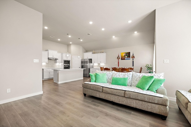 living area featuring light wood finished floors, visible vents, baseboards, lofted ceiling, and recessed lighting