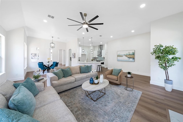 living room featuring arched walkways, dark wood finished floors, visible vents, and recessed lighting