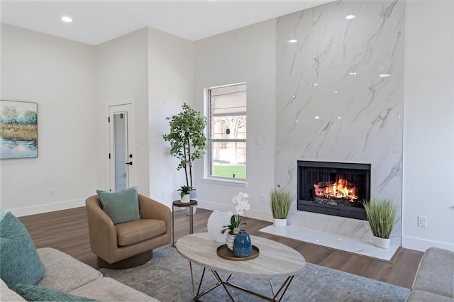 living room with a high end fireplace, recessed lighting, baseboards, and wood finished floors