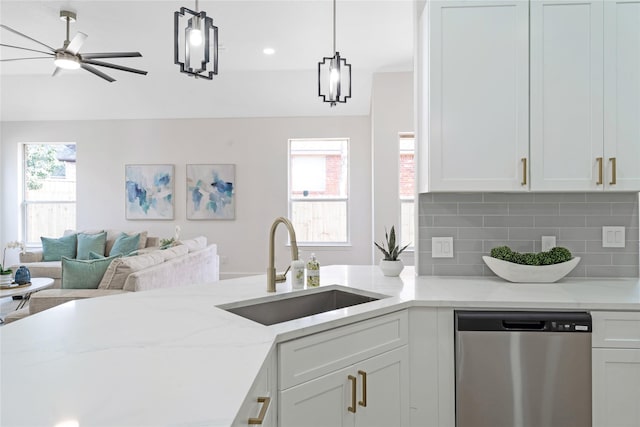 kitchen featuring a wealth of natural light, backsplash, stainless steel dishwasher, white cabinets, and a sink