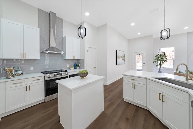 kitchen featuring stainless steel gas stove, wall chimney exhaust hood, dark wood-style flooring, a sink, and backsplash