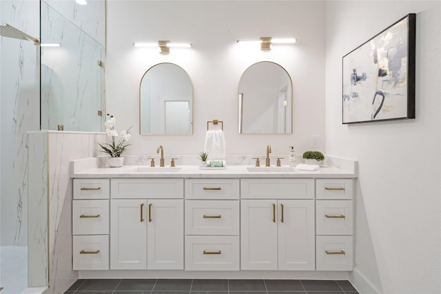 full bathroom with double vanity, a marble finish shower, and a sink