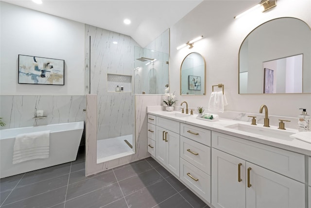 bathroom with a sink, vaulted ceiling, a marble finish shower, tile patterned floors, and double vanity