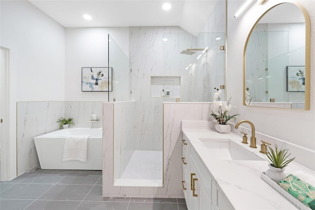 bathroom featuring a marble finish shower, tile patterned floors, vanity, a freestanding tub, and tile walls