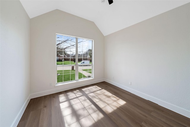 unfurnished room with vaulted ceiling, dark wood-type flooring, and baseboards