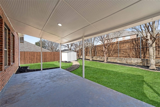 view of patio with an outbuilding, a fenced backyard, and a storage unit