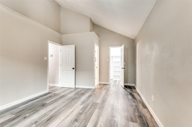 interior space with high vaulted ceiling, baseboards, and wood finished floors