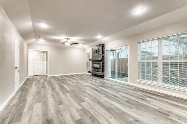 unfurnished living room with light wood finished floors, baseboards, visible vents, ceiling fan, and a fireplace