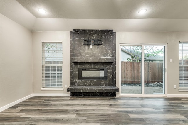 unfurnished living room featuring vaulted ceiling, plenty of natural light, wood finished floors, and baseboards