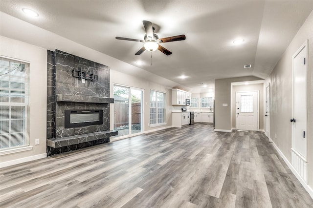 unfurnished living room with lofted ceiling, a large fireplace, baseboards, and wood finished floors