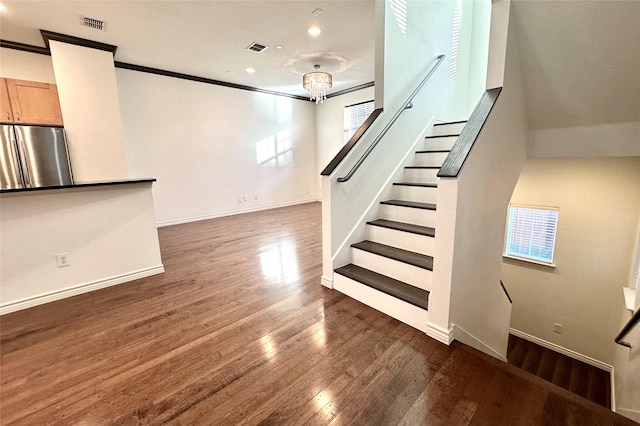 unfurnished living room featuring ornamental molding, dark wood-type flooring, visible vents, and baseboards