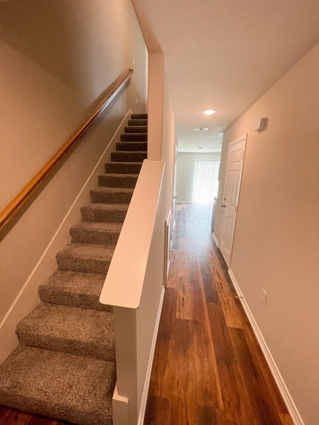 staircase featuring baseboards and wood finished floors