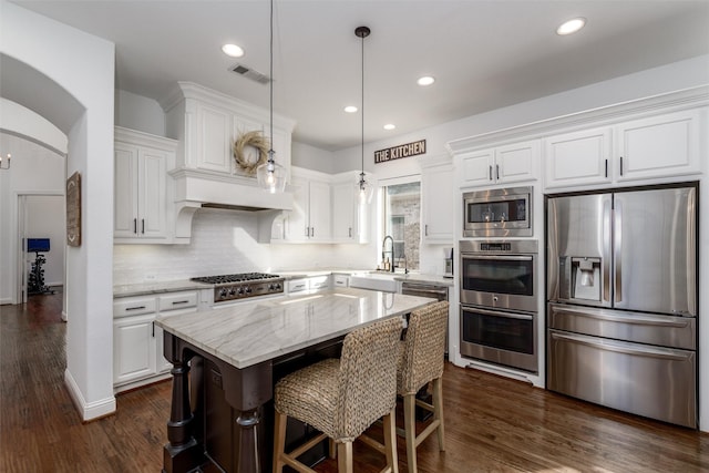 kitchen with white cabinetry, appliances with stainless steel finishes, arched walkways, and a sink