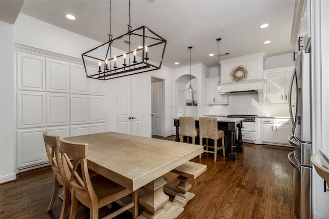 dining space featuring arched walkways, dark wood-style flooring, and recessed lighting