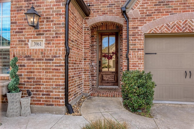 doorway to property featuring a garage and brick siding